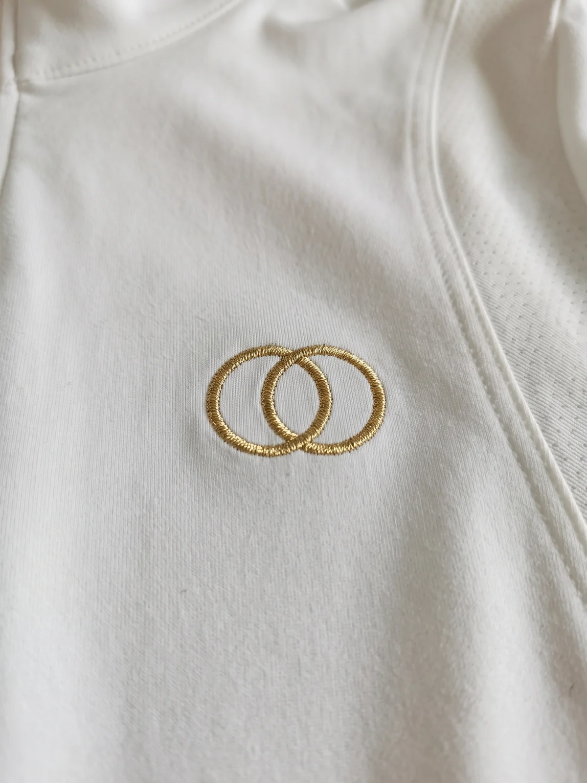 Logo-Stickerei mit metallisch glänzendem Garn auf der Brust eines weißen Turniershirts – KI-generierte Illustration