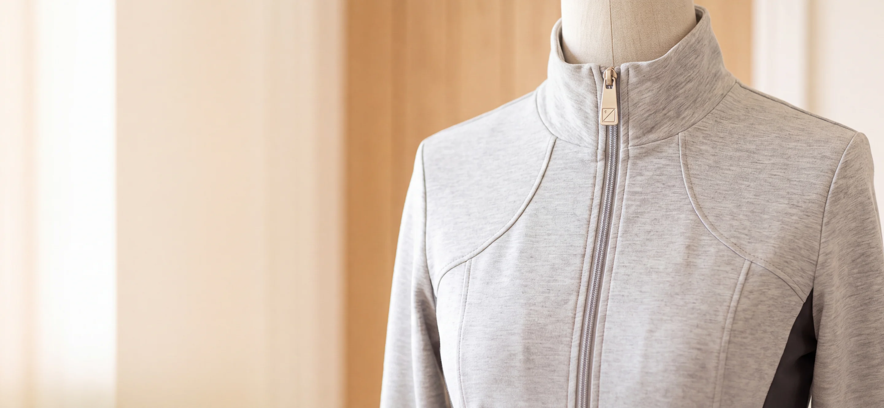 Trainingsjacke in Grau meliert in Nahaufnahme: Stehkragen, Frontreißverschluss und ein Zipper-Puller aus Metall mit Logo – KI-generierte Illustration