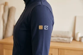 Metallabzeichen und gesticktes Logo am Ärmel einer Trainingsjacke – KI-generierte Illustration