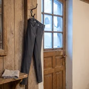 Dunkelgraue Reithose an einer Stalltür im Winterlicht – KI-generierte Illustration