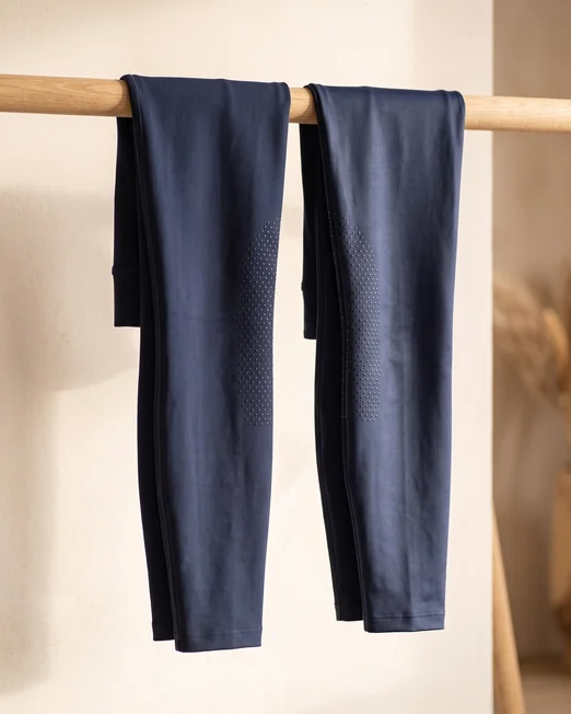Zwei Reitleggings-Beine nebeneinander: matter Kompressionsstoff und leicht glänzender Glanzstoff – KI-generierte Illustration