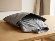 Geöffneter Versandbeutel mit einem getragenen grauen Reitshirt – KI-generierte Illustration