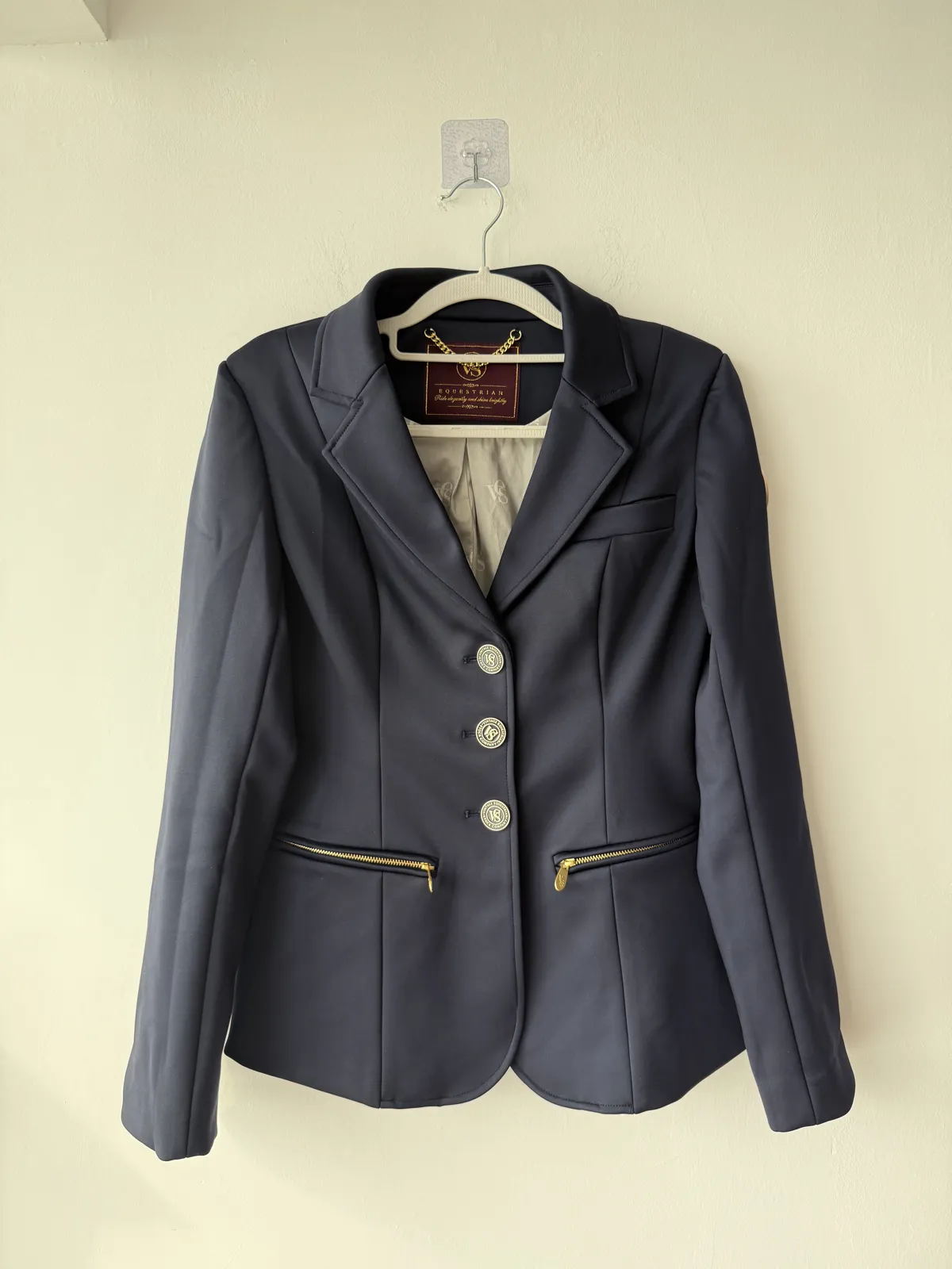 Equestrian Wear Factory Fertigungsmuster: Kragen und Dreiknopf-Leiste eines navyblauen Damen-Turniersakkos auf dem Bügel